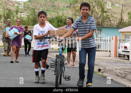 I soldati dell'esercito americano e gli ufficiali della Guardia Nazionale degli Stati Uniti consegnano rifornimenti di emergenza ai residenti portoricani durante gli sforzi di soccorso in seguito all'uragano Maria 14 ottobre 2017 a Borinquen, Aguadilla, Porto Rico. (Foto di Alexis Velez via Planetpix) Foto Stock