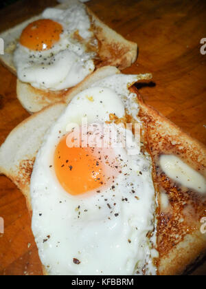 Uovo fritto su toast imburrato con incrinato pepe nero Foto Stock