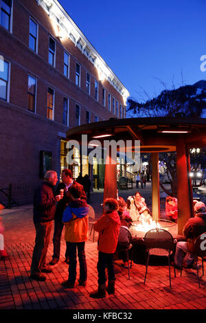 Stati Uniti d'America, colorado, Aspen, persone warm up dal fuoco in sqare nel centro di Aspen al crepuscolo Foto Stock