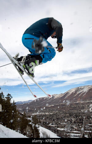 Stati Uniti d'America, colorado, Aspen, sciatore prendere l'aria su un sentiero denominato cavatappi con la città di Aspen in distanza, aspen ski resort, monte Ajax Foto Stock