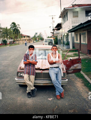 PANAMA, PANAMA, Bocas del Toro, giovani uomini in appoggio contro la loro auto sulla strada principale, America Centrale Foto Stock