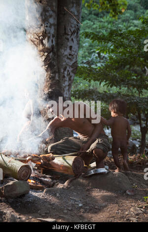 Filippine, palawan barangay regione, pollo essendo preparato e cotto su un fuoco aperto in villagen kalakwasan noli con i suoi due figli Foto Stock