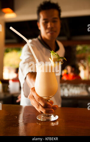 Filippine, palawan el nido, lagen island, il Barista serve una pina colada a lagen island resort in bacuit bay nel mare della cina del sud Foto Stock