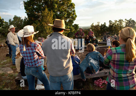 Stati Uniti d'America, Wyoming encampment, gli ospiti di un dude ranch sedersi intorno a un falò e ascoltare un uomo suonare la chitarra e cantare canzoni country western, abara ranch Foto Stock