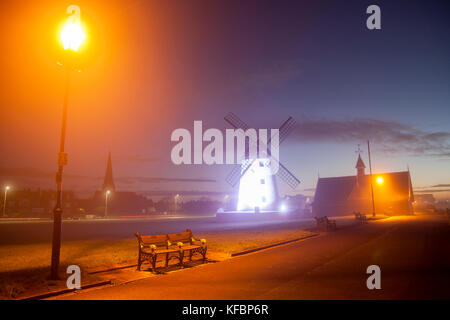 Lytham St Annes, Lancashire, Regno Unito Meteo. 27th Ottobre 2017. Un inizio luminoso ma freddo al giorno con tutta la nebbia o macchie di nebbia che si liberano per lasciare una fine, giorno con incantesimi di sole. Il sole sorge e illumina i cieli dietro il mulino a vento a LED della Torre. Lytham Windmill si trova sul Green nella cittadina costiera di Lytham St Annes, Lancashire, Inghilterra. È del tipo noto come mulino a torre ed è stato progettato per macinare grano e avena per produrre farina o crusca. Credit; MediaWorldImages/AlamyLiveNews Foto Stock