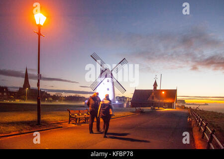 Lytham St Annes, Lancashire, Regno Unito Meteo. 27th Ottobre 2017. Un inizio luminoso ma freddo al giorno con tutta la nebbia o macchie di nebbia che si liberano per lasciare una fine, giorno con incantesimi di sole. Il sole sorge e illumina i cieli dietro il mulino a vento a LED della Torre. Lytham Windmill si trova sul Green nella cittadina costiera di Lytham St Annes, Lancashire, Inghilterra. È del tipo noto come mulino a torre ed è stato progettato per macinare grano e avena per produrre farina o crusca. Credit; MediaWorldImages/AlamyLiveNews Foto Stock