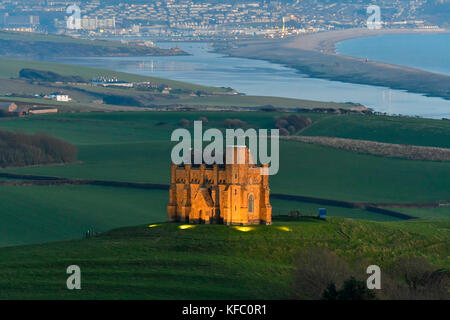 Abbotsbury, Dorset, Regno Unito. Il 27 ottobre 2017. Regno Unito Meteo. Santa Caterina la cappella a Abbotsbury nel Dorset è illuminato al tramonto per l annuale luminarie incantata evento a Abbotsbury giardini subtropicali in una serata di cielo sereno e venti leggeri con una vista lungo la flotta verso l'isola di Portland. Il giorno finale di luminarie presso i giardini è domenica 29 ottobre. Photo credit: Graham Hunt/Alamy Live News Foto Stock