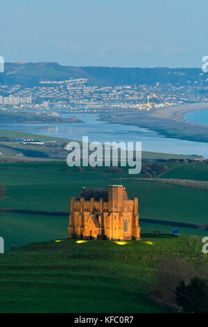 Abbotsbury, Dorset, Regno Unito. Il 27 ottobre 2017. Regno Unito Meteo. Santa Caterina la cappella a Abbotsbury nel Dorset è illuminato al tramonto per l annuale luminarie incantata evento a Abbotsbury giardini subtropicali in una serata di cielo sereno e venti leggeri con una vista lungo la flotta verso l'isola di Portland. Il giorno finale di luminarie presso i giardini è domenica 29 ottobre. Photo credit: Graham Hunt/Alamy Live News Foto Stock