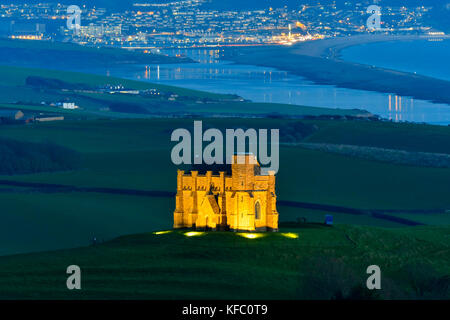 Abbotsbury, Dorset, Regno Unito. Il 27 ottobre 2017. Regno Unito Meteo. Santa Caterina la cappella a Abbotsbury nel Dorset è illuminato al tramonto per l annuale luminarie incantata evento a Abbotsbury giardini subtropicali in una serata di cielo sereno e venti leggeri con una vista lungo la flotta verso l'isola di Portland. Il giorno finale di luminarie presso i giardini è domenica 29 ottobre. Photo credit: Graham Hunt/Alamy Live News Foto Stock