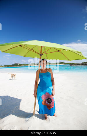 EXUMA, Bahamas. Nicole giocando e portando un ombrello su un sandbar. Foto Stock