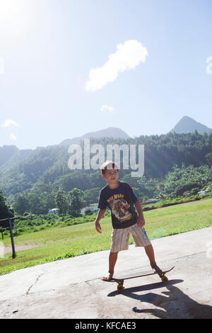 Polinesia Francese, Moorea. Bambini locali lo skateboard e mountain bike. Foto Stock