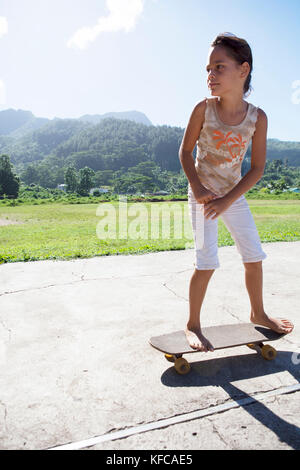 Polinesia Francese, Moorea. Bambini locali lo skateboard e mountain bike. Foto Stock