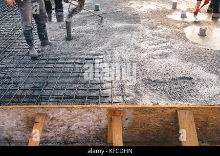 La gettata di calcestruzzo durante la cementificazione commerciale pavimenti degli edifici in costruzione - Lastra di calcestruzzo Foto Stock