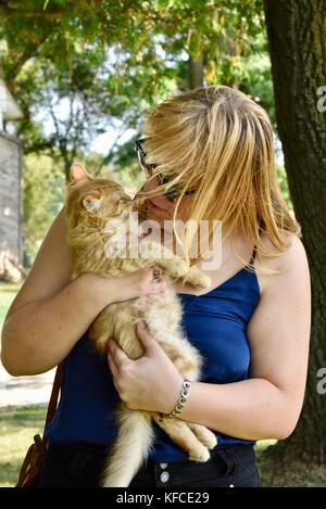 Donna che gioca con cat durante il tour della fattoria di capre che fornisce latte a door county creamery in door county comunità di suor Bay, Wisconsin, Stati Uniti d'America. Foto Stock