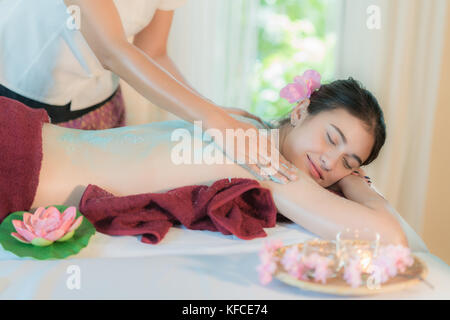 Giovane donna asiatica la ricezione sale massaggio nella spa salone, mettendo mano scrub al sale sul retro femmina, spa concept Foto Stock