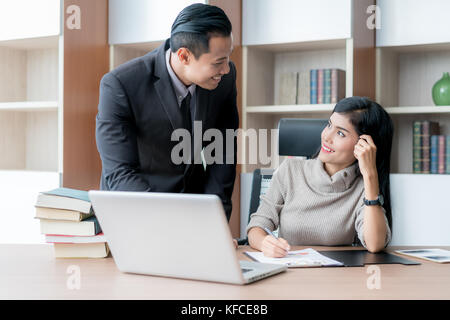 Due colleghi asian imprenditore e imprenditrice utilizzando laptop mentre si lavora sul nuovo progetto di business, due giovani professionisti datori di lavoro lavorando su por Foto Stock
