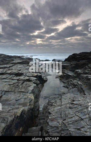 Le rocciose e frastagliate a pressione atmosferica Cornish Coast su una burrascosa serata al Tramonto in Cornovaglia. scene costiere, Cornwall, crepuscolo o tramonto su una serata di tempesta Foto Stock