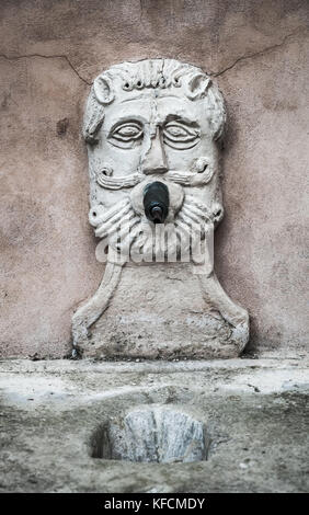 Antica fontana con acqua potabile nella forma di un viso maschile. fermo, Italia Foto Stock