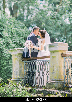 Baciare gli sposi sul vecchio balcone. a tutta lunghezza vista. Foto Stock