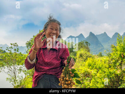 Stock photo - Donna vendita di frutti di Yangshuo, Cina presso il drago ponte che attraversa il fiume li Foto Stock