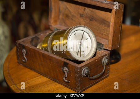 Antique golden compass all'interno di una scatola di legno su un tavolo. Foto Stock