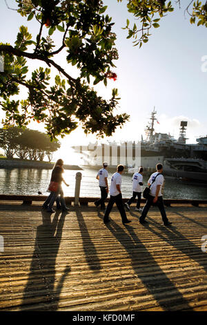 Stati Uniti, California, San Diego, un gruppo di individui a piedi lungo la baia di San Diego verso la USS Midway Museum Foto Stock