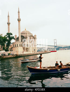 Turchia, Istanbul, ragazzi adolescenti sulla barca con la Moschea Ortakoy in background Foto Stock