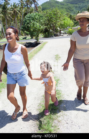 Polinesia francese, Tahaa Island. Famiglia locale a piedi lungo la strada. Foto Stock