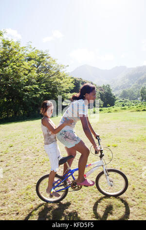 Polinesia Francese, Moorea. Bambini locali lo skateboard e mountain bike. Foto Stock