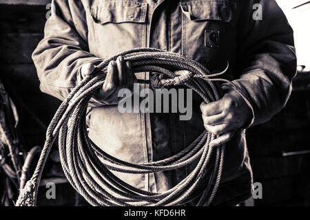 Stati Uniti d'America, oregon, enterprise, cowboy todd nash mantiene la sua corda a snyder ranch dopo una lunga giornata di bovini in movimento sotto la pioggia, nordest oregon Foto Stock