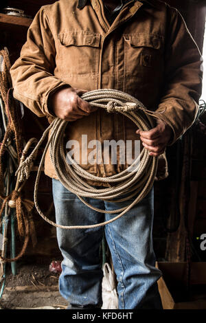 Stati Uniti d'America, oregon, enterprise, cowboy todd nash mantiene la sua corda a snyder ranch dopo una lunga giornata di bovini in movimento sotto la pioggia, nordest oregon Foto Stock