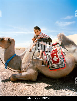 MONGOLIA, Nemegt Basin, un ragazzo e il suo cammello si riposano, il deserto di Gobi Foto Stock