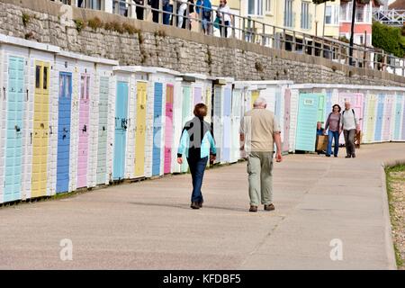 La gente a piedi dalla spiaggia di capanne sul lungomare di Lyme Regis Dorset England Regno Unito Foto Stock