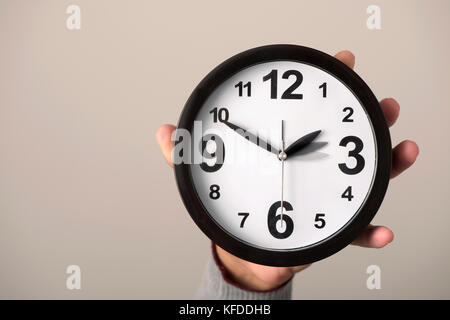 Primo piano della mano di un giovane uomo caucasico tenendo un orologio che è essendo regolata in avanti o indietro di un'ora alla fine o all'inizio di th Foto Stock