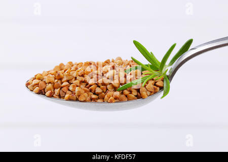 Cucchiaio di materie del grano saraceno in bianco sullo sfondo di legno Foto Stock