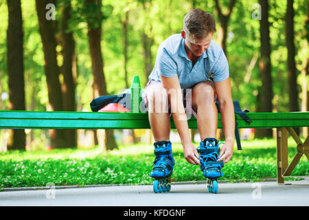 Giovane ragazzo bello lacci di legatura sul suo inline pattini a rotelle. Foto Stock