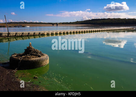 Ancoraggio del pneumatico sulla riva di un serbatoio con acqua sfuggente linea in acqua bewl, Kent, con acqua verde in una giornata di sole con nuvole blu acqua riflessa Foto Stock