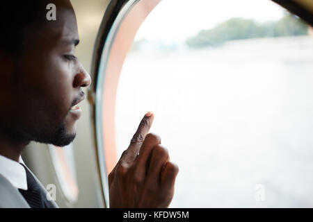 Vista del profilo di un pensivo uomo afroamericano che gode di una vista pittoresca dalla finestra della cabina della nave, ritratto di testa e spalle Foto Stock