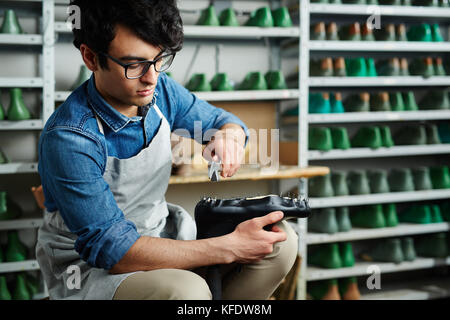 Giovani professionisti cobbler tenendo i chiodi dal pezzo scarpa in cuoio nero Foto Stock