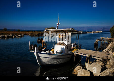 Una barca da pesca in un canale, fiume, vicino alla città di Lefkimmi, Isole Ionie, Grecia. Cielo blu, il sole, vacanze in area mediterranea. Foto Stock