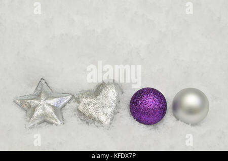 Close up di argento e viola per albero di Natale decorazioni su sfondo di neve Foto Stock