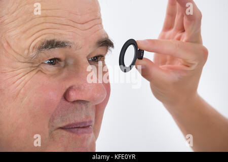 Close-up di un'all'ottico optometrista esaminando senior paziente di sesso maschile è vista con telaio di prova Foto Stock