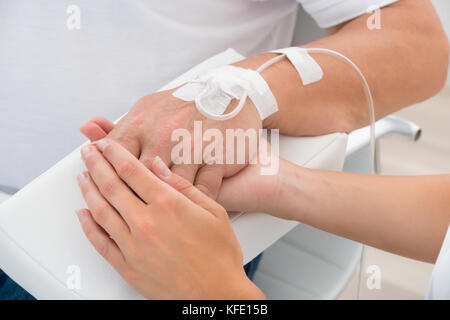 Close-up di un medico tenendo mano del paziente con flebo IV Foto Stock