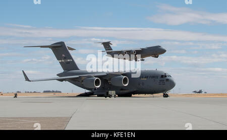 C-5 M Super Galaxy da Dover Air Force Base, Delaware, rende il suo approccio finale come un -17 Globemaster III parcheggiato sulla rampa è sottoposto a manutenzione, Ott. 19 Foto Stock