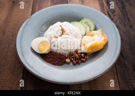 Cibo malese/cucina (nasi lemak) - riso in bianco con uovo fritto,acciughe,salsa piccante (sambal) e noccioline tutti messi insieme in una piastra Foto Stock