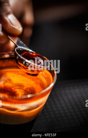 Immagine ravvicinata di barman versa manualmente alcol da misurino in un bicchiere da cocktail Foto Stock