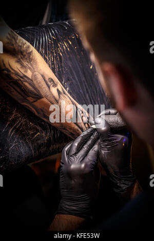 Close up tattoo artist dimostra il processo per ottenere il nero tattoo Foto Stock