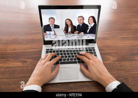 Close-up di imprenditore le videoconferenze su laptop alla scrivania in ufficio Foto Stock