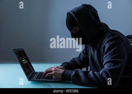 Il pirata informatico di rubare informazioni dal computer portatile in ufficio di notte Foto Stock