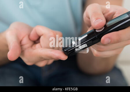 Close-up di persona le mani misurando i livelli di zucchero nel sangue con il glucometro Foto Stock